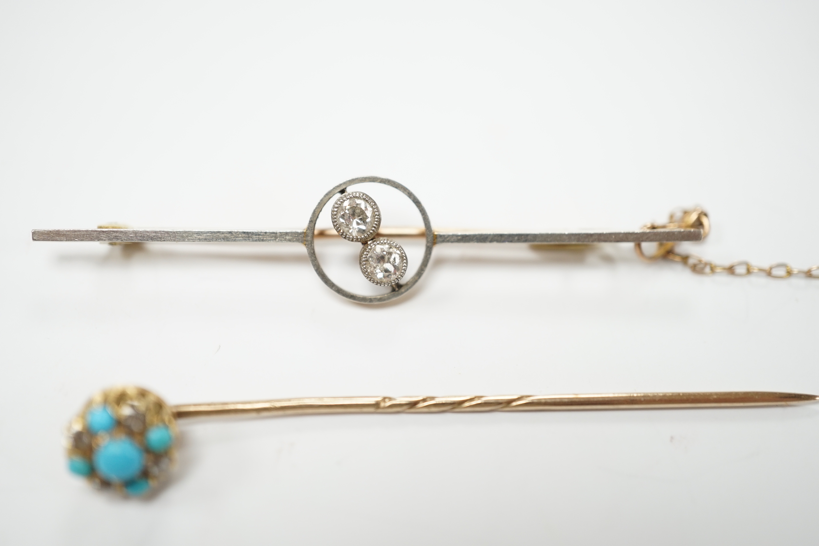 An early 20th century yellow metal, white metal and two stone diamond crossover set bar brooch, 57mm and a similar turquoise and diamond cluster set stick pin.
